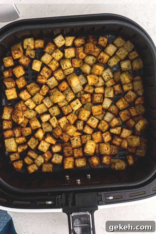 Crispy Air Fryer Breakfast Potatoes Recipe 5 Golden, seasoned cubes of potatoes, in an air fryer basket after being cooked.