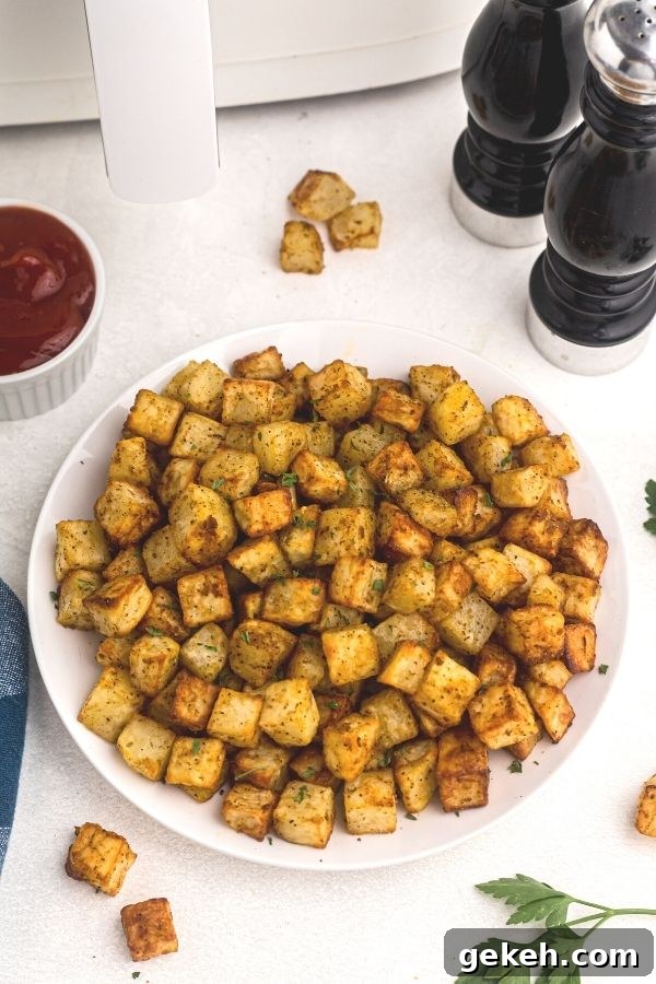 Crispy Air Fryer Breakfast Potatoes Recipe 6 Golden bites of breakfast potato on a white plate.
