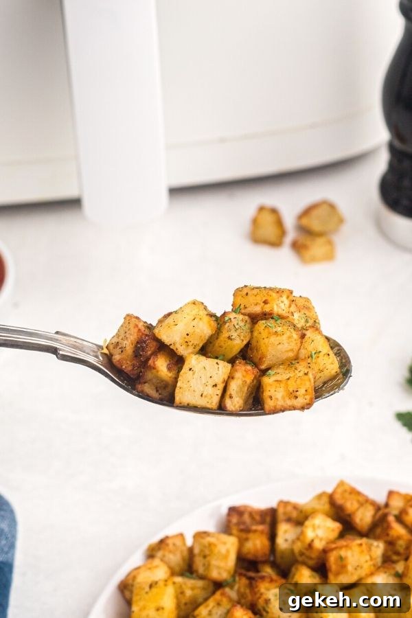 Crispy Air Fryer Breakfast Potatoes Recipe 7 Spoonful of golden breakfast potatoes, cooked and garnished with parsley flakes.
