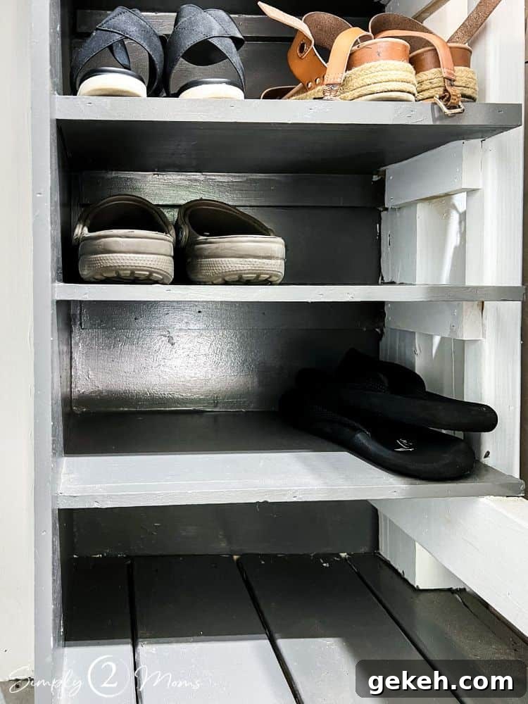 Close up of shoe shelves built into a wall in a garage that attach to the wood steps and deck.