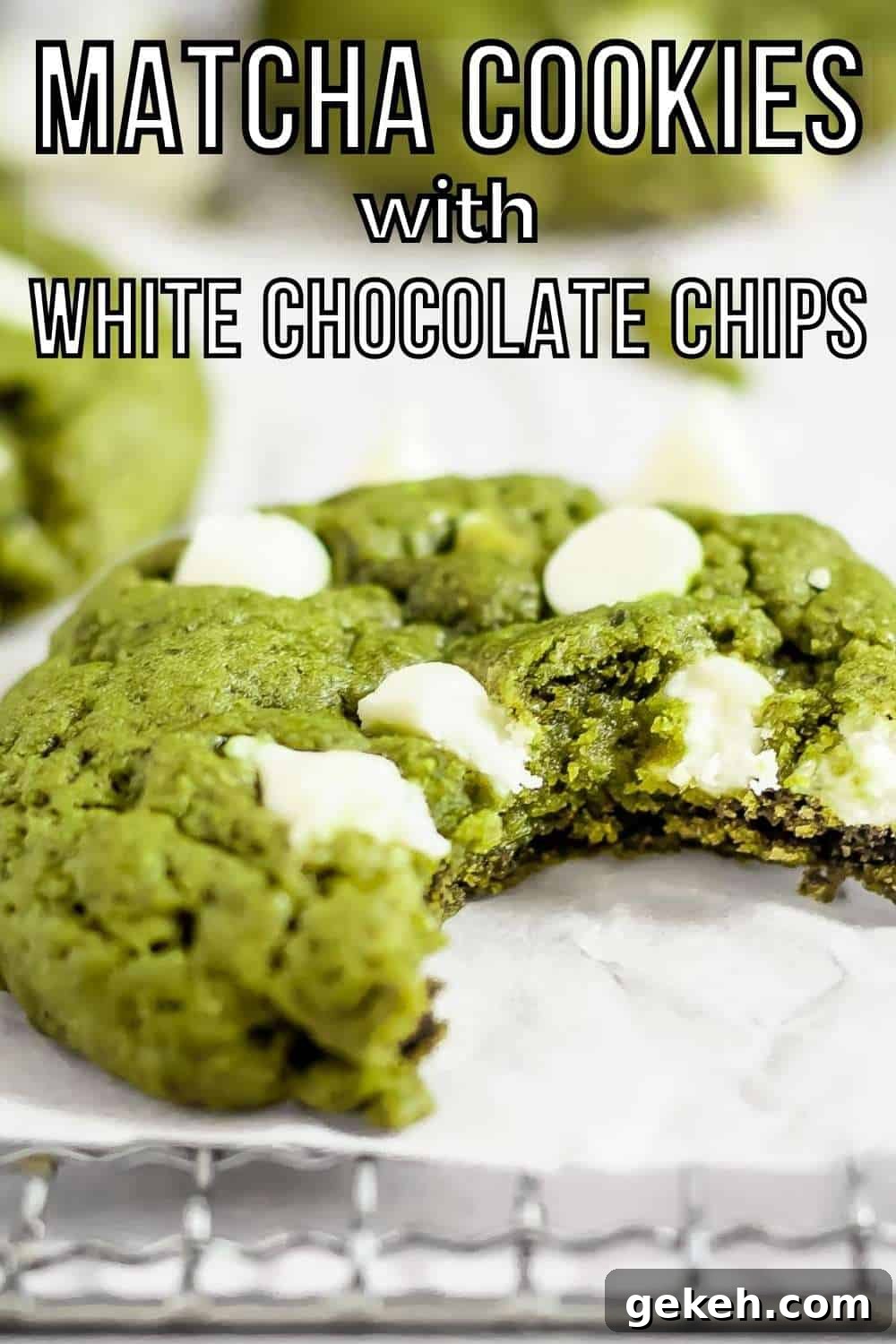 Side shot of a green matcha cookie with a bite taken out on a drying rack with parchment paper with more cookies and white chocolate in the background.