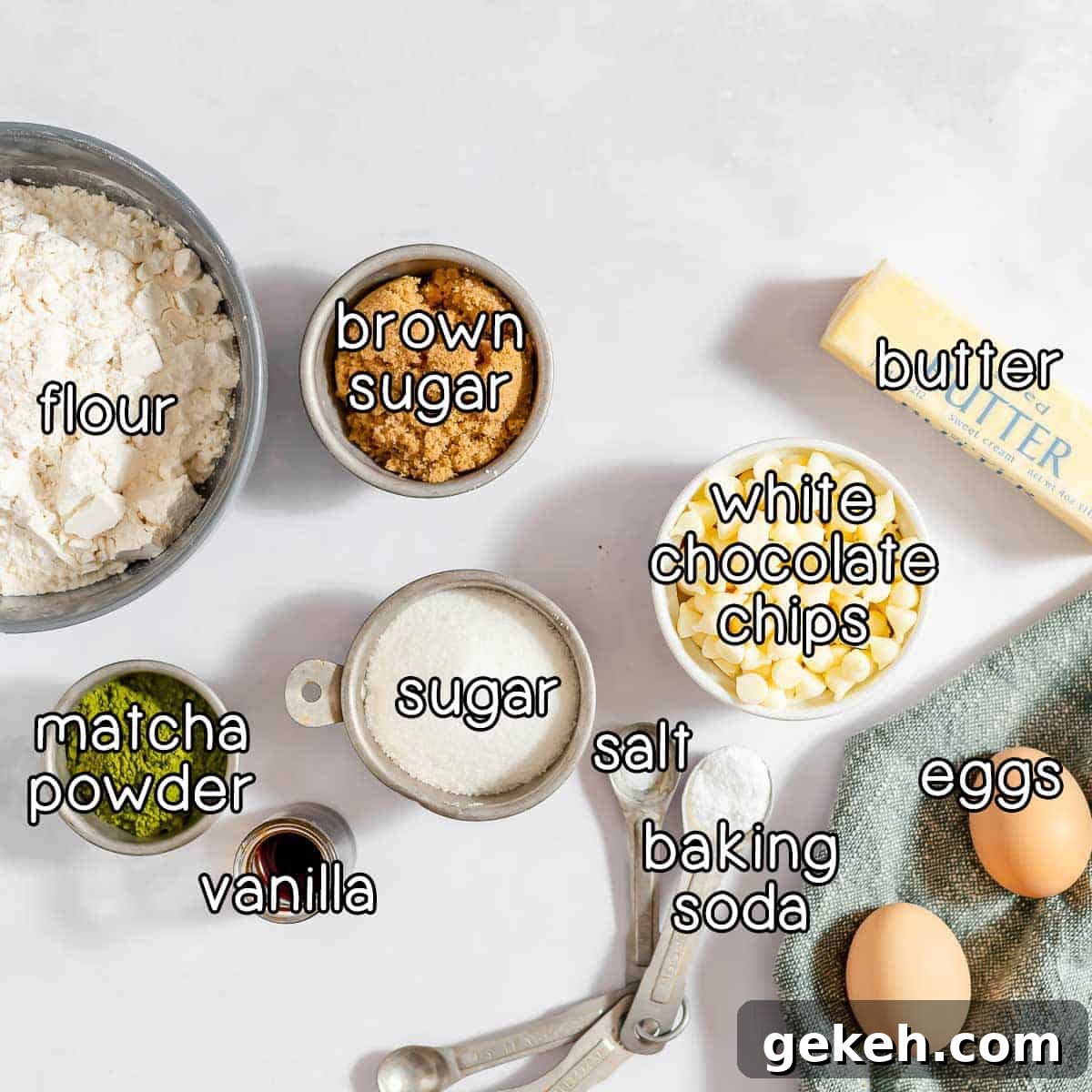 Overhead shot of ingredients - flour, brown sugar, butter, white chocolate chips, sugar, matcha powder, vanilla, salt, baking soda, and eggs.