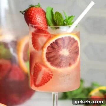 Rose sangria with fruit and a straw.