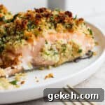 Crispy Panko-Crusted Salmon with Lemon Garlic Butter 8 Side shot of a piece of panko crusted salmon on a white plate with the tip of a gold fork in the bottom right hand corner.