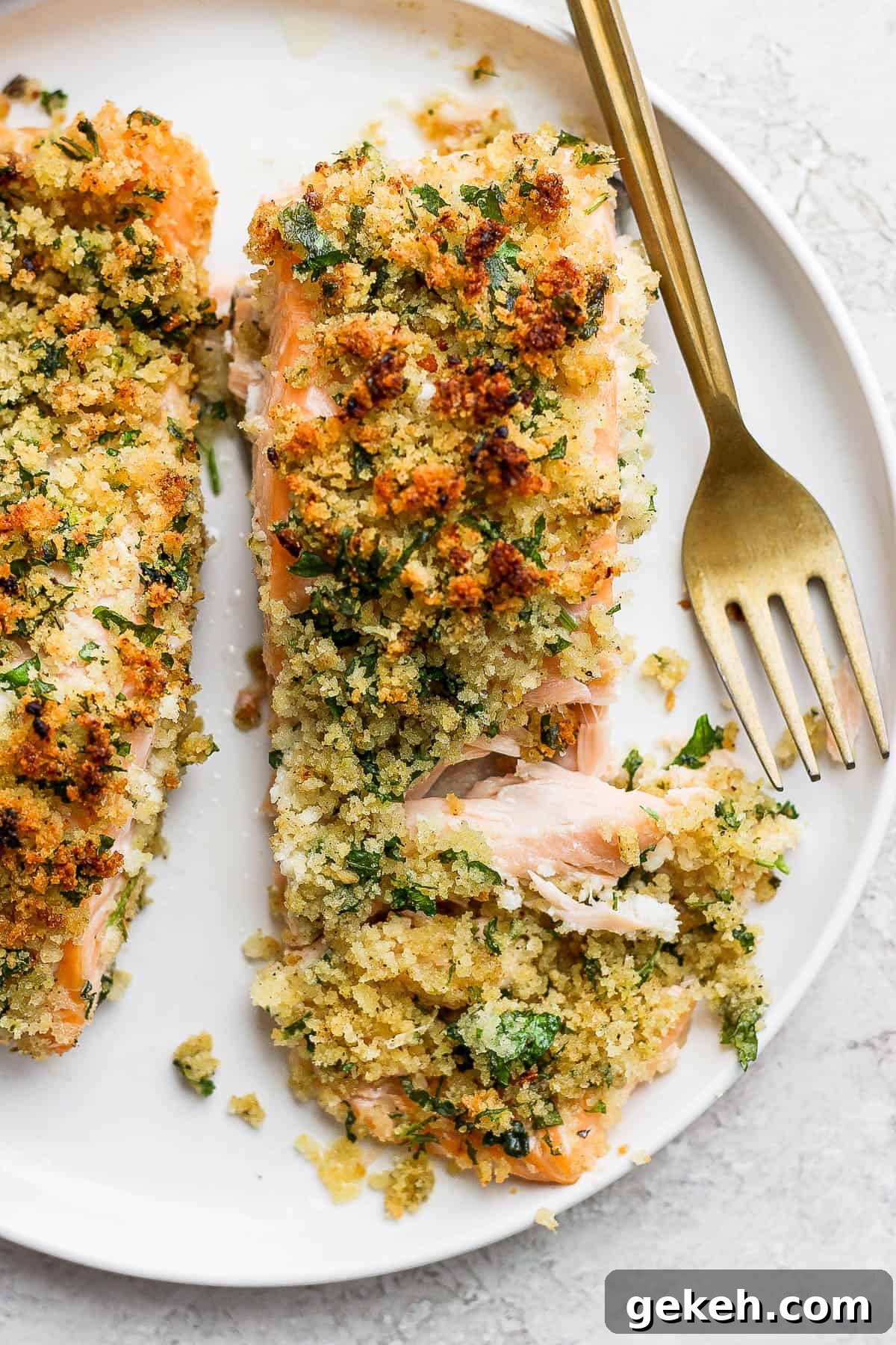 Crispy Panko-Crusted Salmon with Lemon Garlic Butter 7 A panko salmon fillet on a plate with a chunk pulled out by a gold fork.