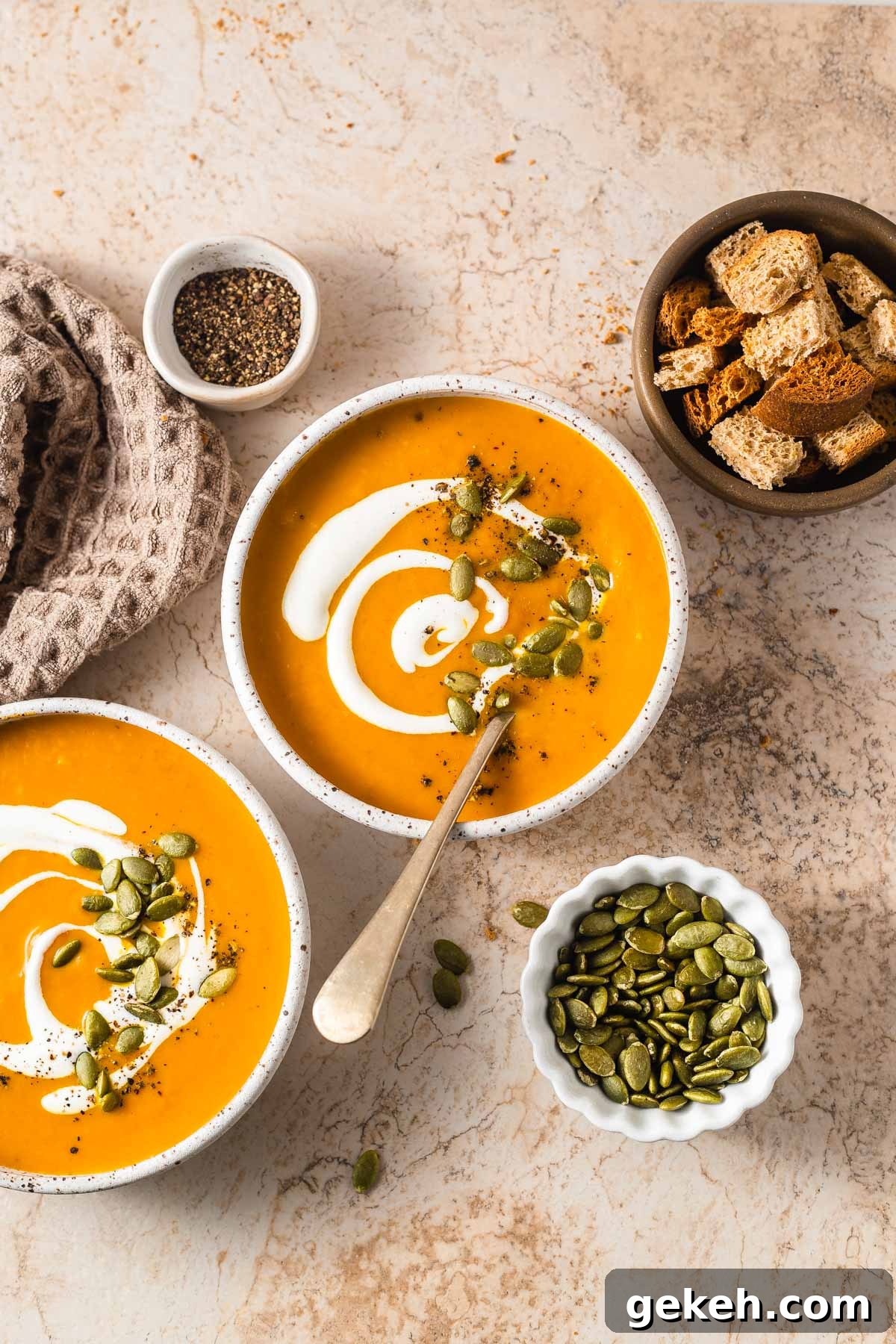 Creamy Low-Carb Keto Pumpkin Soup Recipe 2 keto pumpkin soup bowls with croutons and pepitas