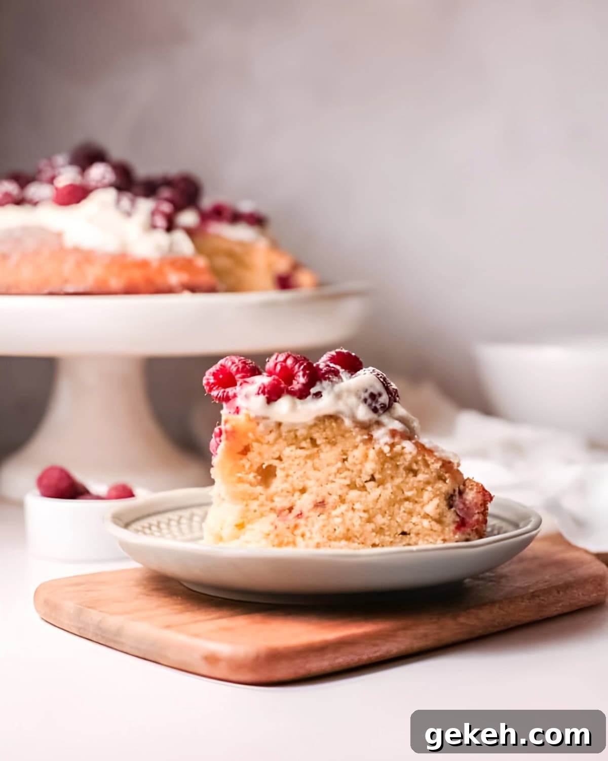 a slice of olive oil cake topped with whipped cream and fresh raspberries on a plate.