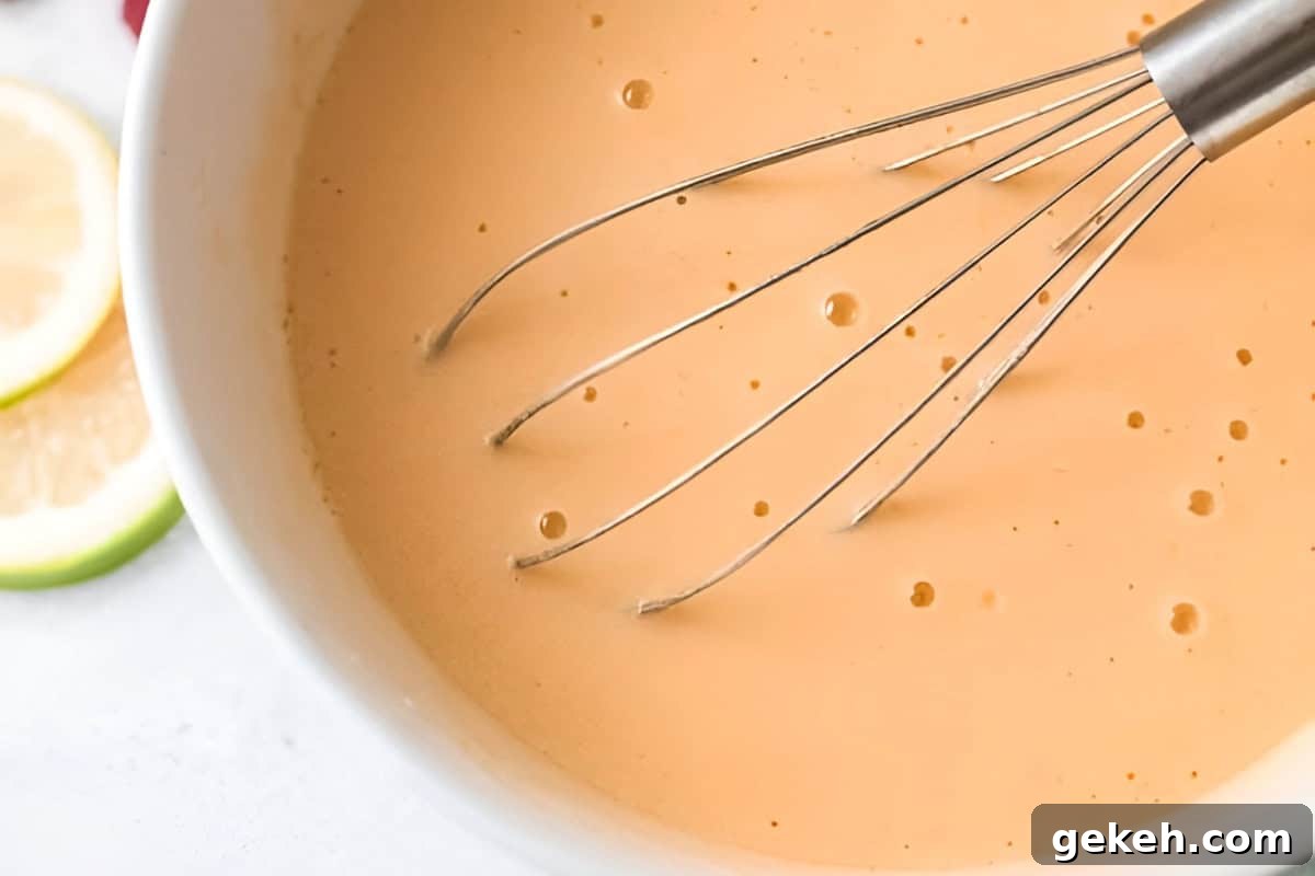 whisked eggs, olive oil, and greek yogurt in a white bowl with a whisk.