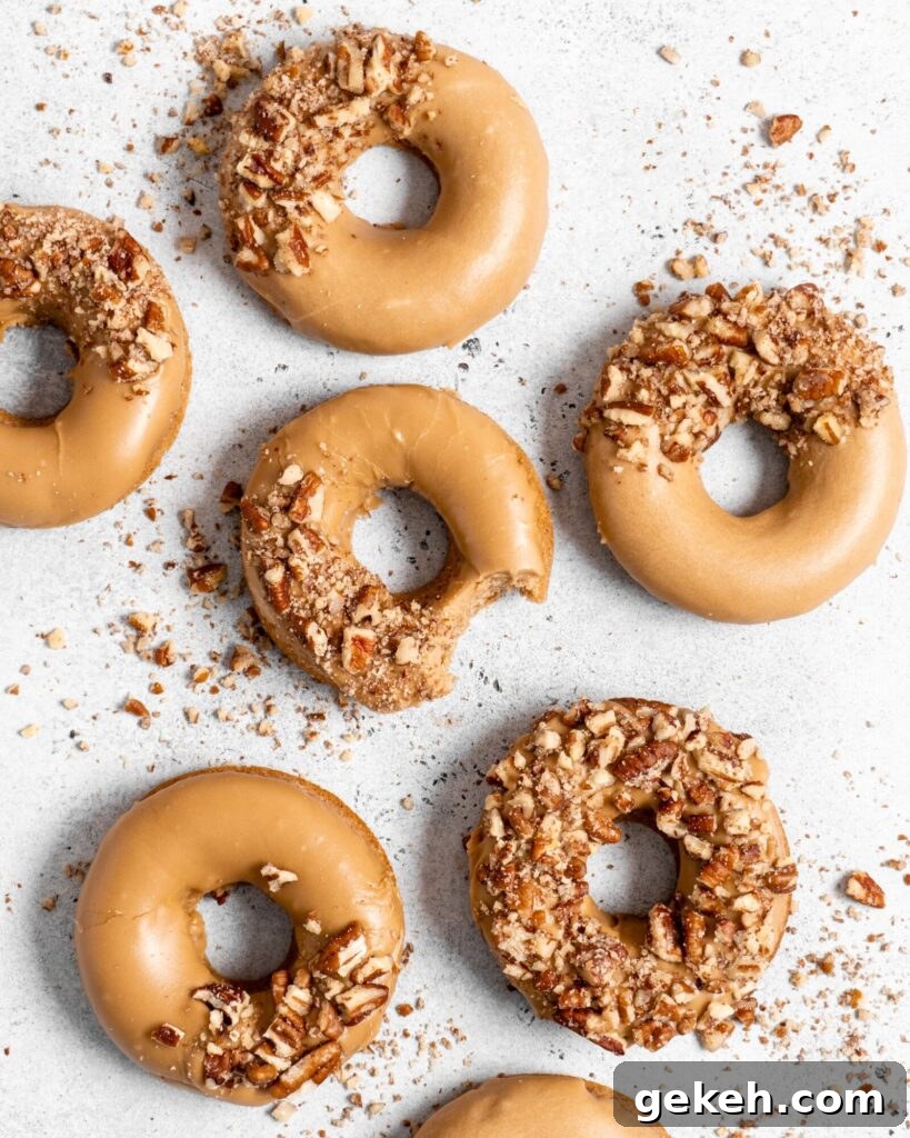 Baked Spiced Brown Sugar Donuts are glazed in a butter maple glaze and garnished with a crushed pecan crust