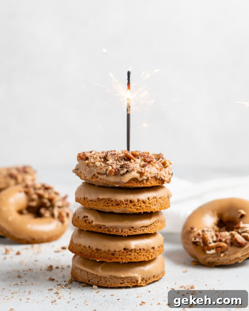Baked Spiced Brown Sugar Donuts are glazed in a butter maple glaze and garnished with a crushed pecan crust