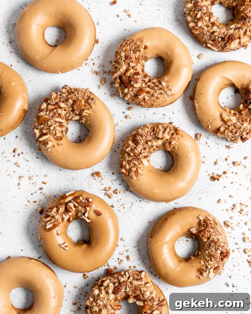 Baked Spiced Brown Sugar Donuts are glazed in a butter maple glaze and garnished with a crushed pecan crust