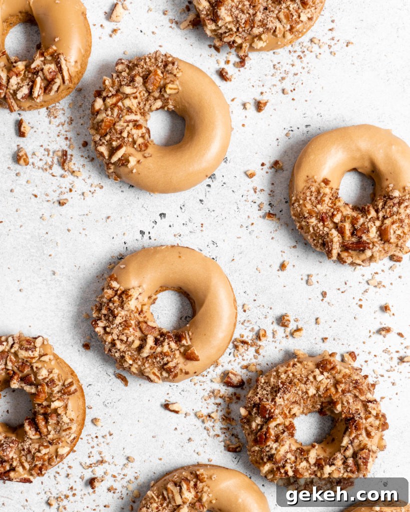Baked Spiced Brown Sugar Donuts are glazed in a butter maple glaze and garnished with a crushed pecan crust