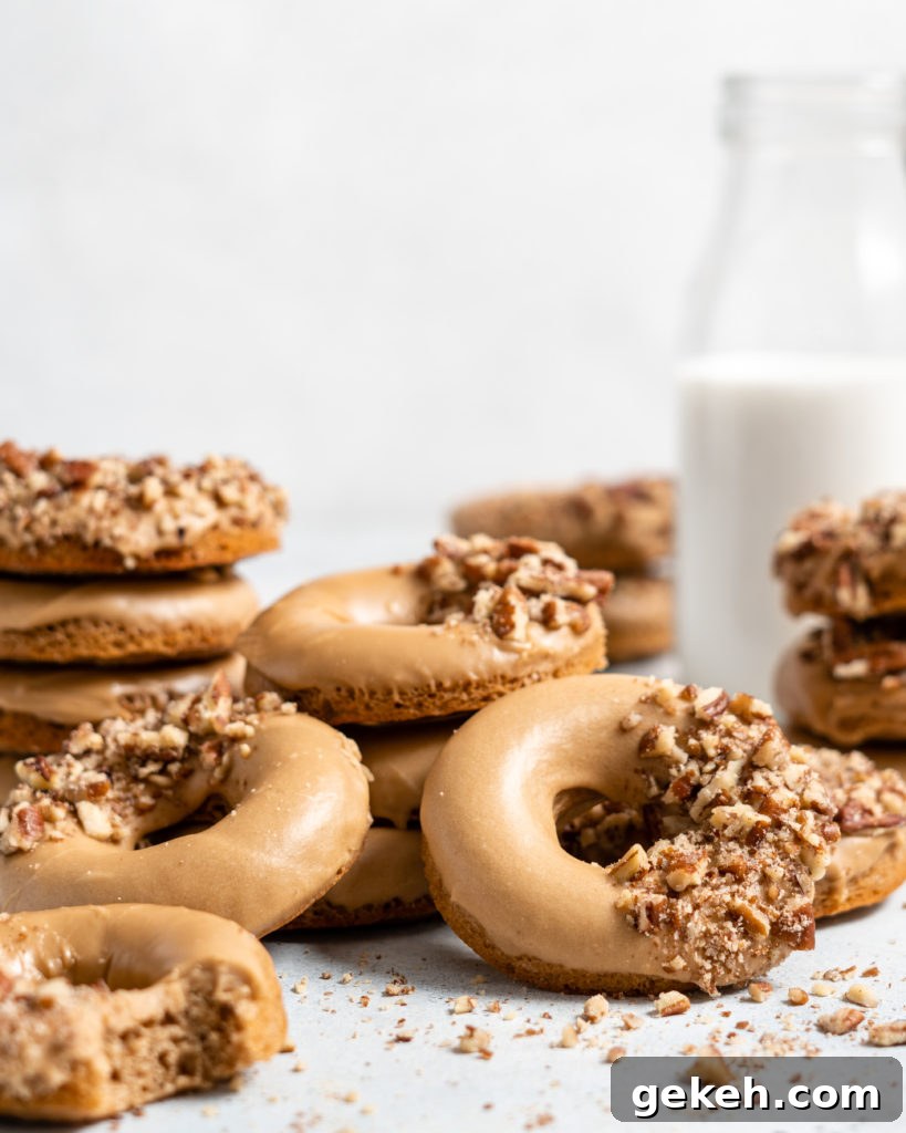 Baked Spiced Brown Sugar Donuts are glazed in a butter maple glaze and garnished with a crushed pecan crust