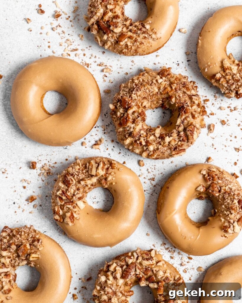Baked Spiced Brown Sugar Donuts are glazed in a butter maple glaze and garnished with a crushed pecan crust