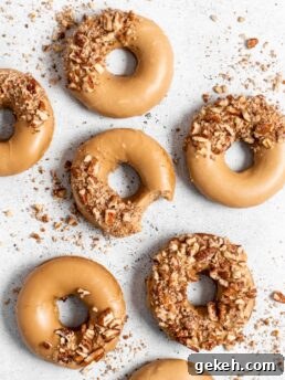 Baked Spiced Brown Sugar Donuts are glazed in a butter maple glaze and garnished with a crushed pecan crust