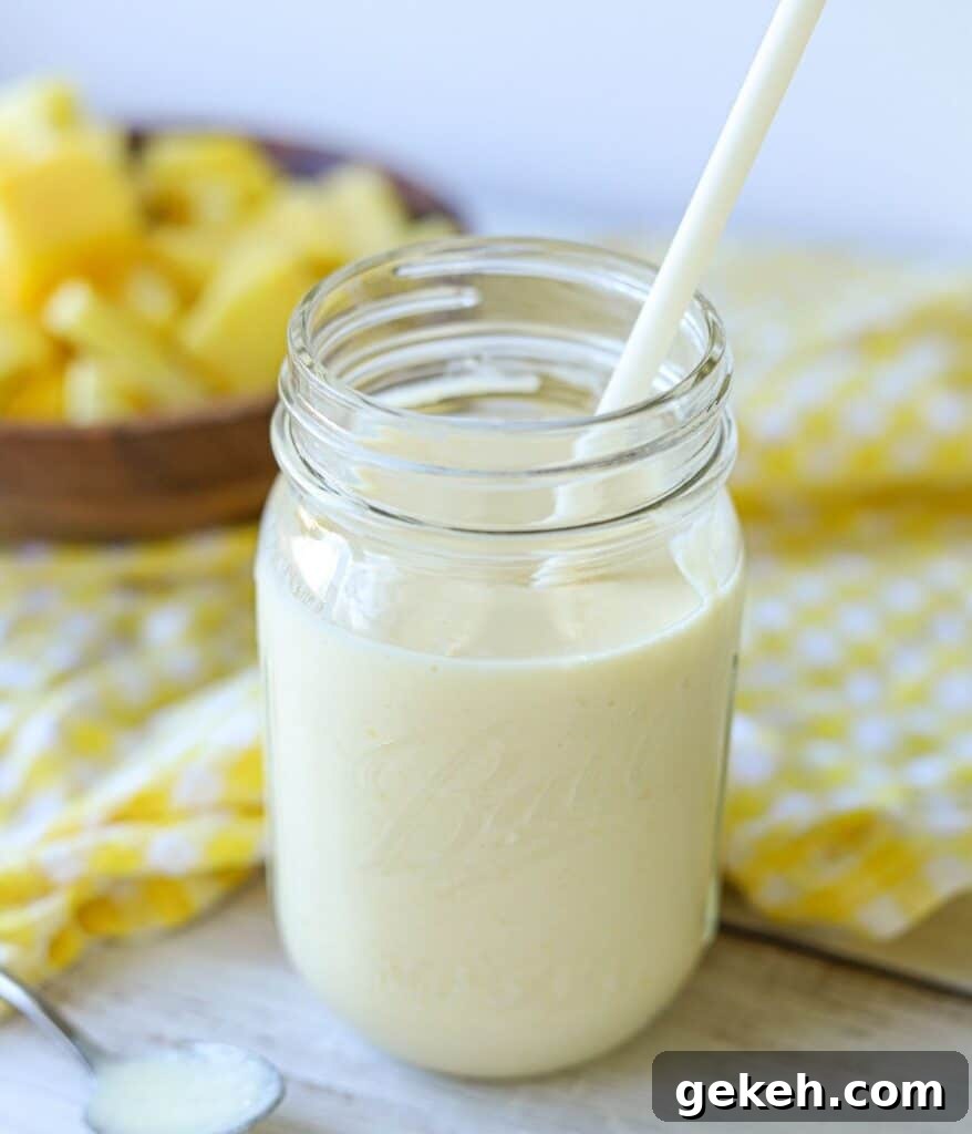 Refreshing Mango Pineapple Smoothie Recipe for Tropical Flavor 4 mason jar full of mango pineapple smoothie with yellow and white checkered napkin and wooden bowl full of pineapple and mango