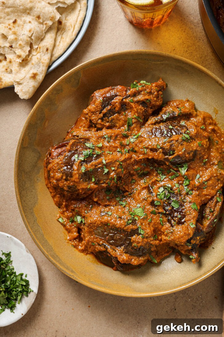 Bagara Baingan: Authentic South Indian Eggplant Curry Recipe 5 Bagare Baingan in a plate garnished with minced cilantro with a plate of roti on the side.