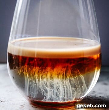 A shot glass sitting on the counter with cocktail resembling jellyfish.