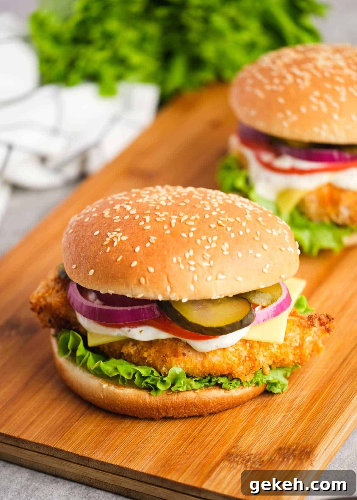Crispy Air Fryer Chicken Sandwich Recipe 17 two crispy chicken sandwiches with tomatoes, cheese, mayo, pickles, red onions, and lettuce with a sesame bun