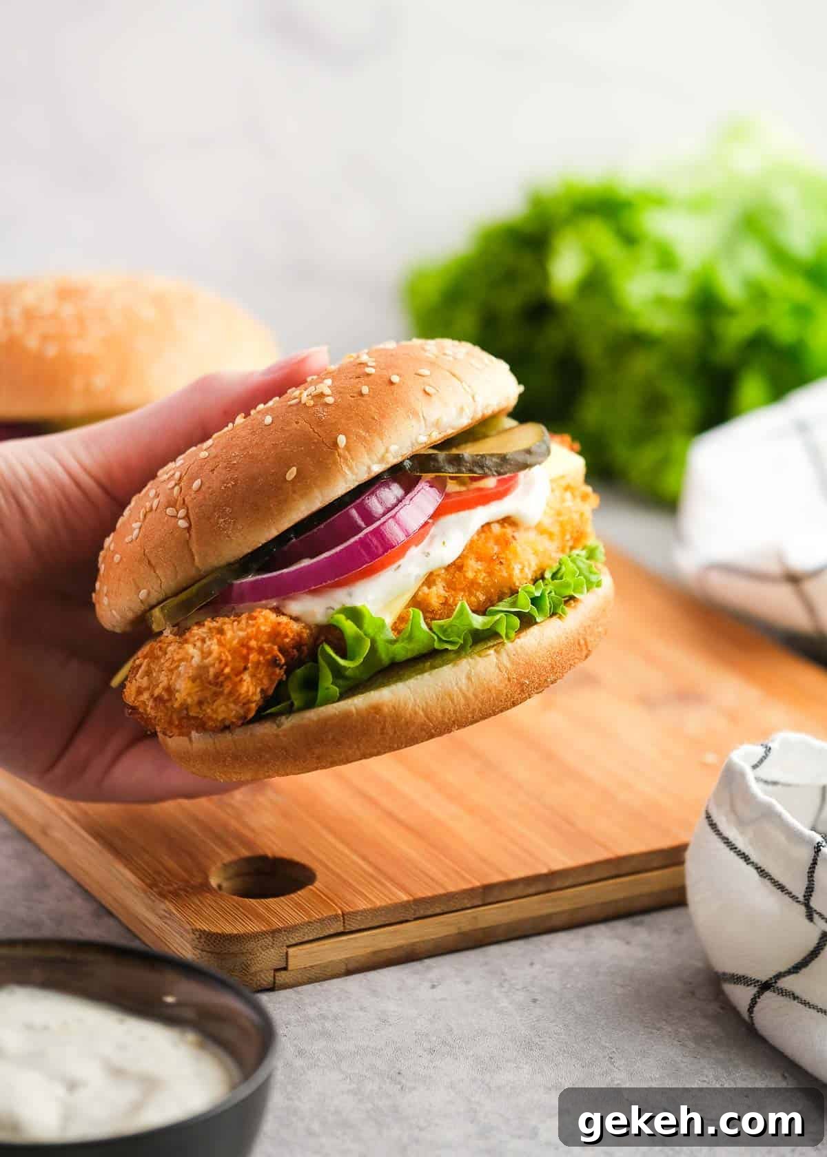 Crispy Air Fryer Chicken Sandwich Recipe 5 a juicy breaded chicken sandwich held over a wooden cutting board