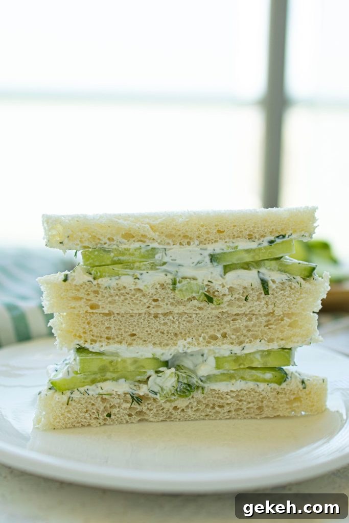 Refreshing Cucumber and Dill Tea Sandwiches for Entertaining 2 Two halves of cucumber and dill sandwiches stacked on a plate.
