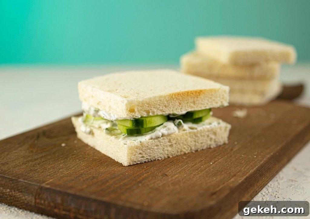 Refreshing Cucumber and Dill Tea Sandwiches for Entertaining 7 Sandwiches being stacked on a wooden cutting board.