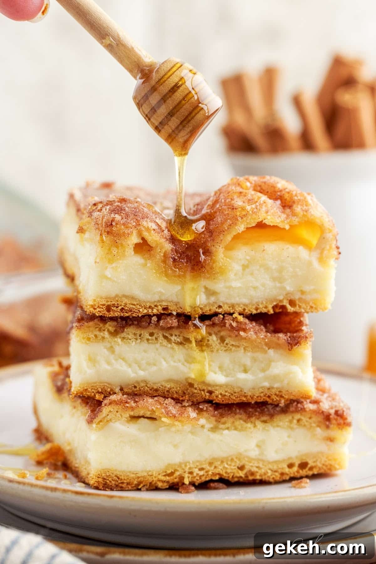 Three slices of Sopapilla Cheesecake stacked on each other drizzled with honey.