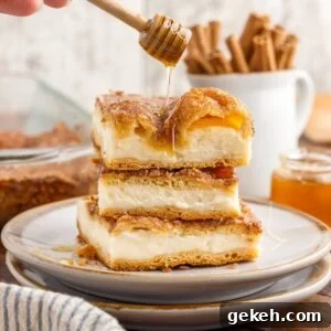 Three slices of Sopapilla Cheesecake stacked on each other drizzled with honey.