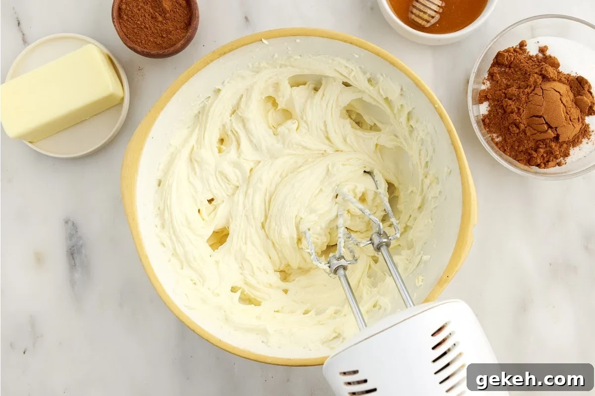 Cream cheese vanilla and sugar mixed in a mixing bowl with a hand mixer.