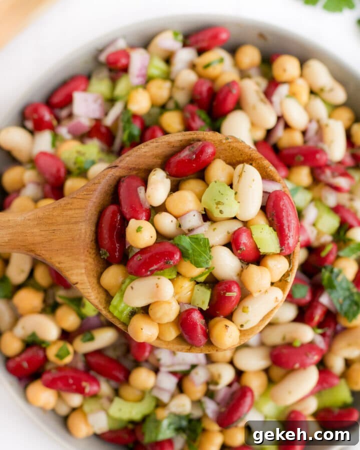 three bean salad being scooped by a wooden spoon