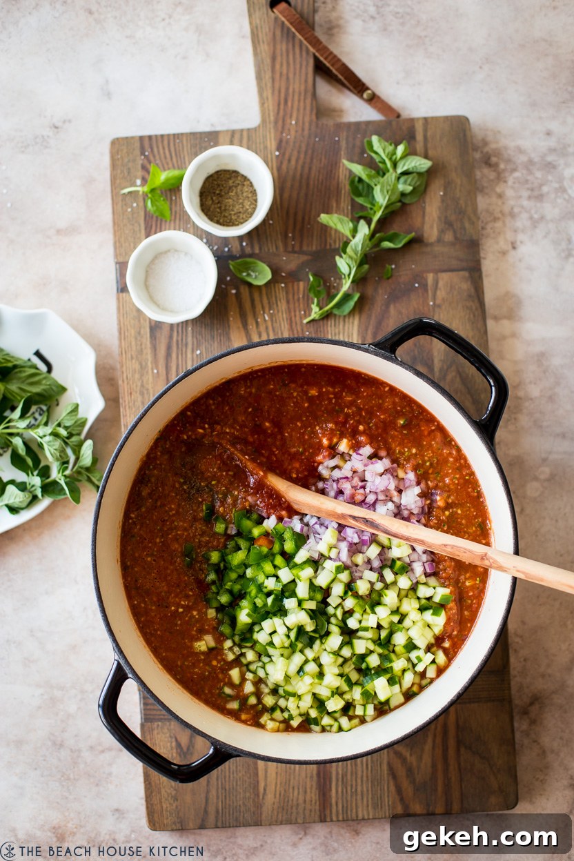Authentic Spanish Gazpacho Recipe: Refreshing Cold Tomato Soup 8 Overhead photo of a pot filled with gazpacho tomato soup topped with chopped vegetables