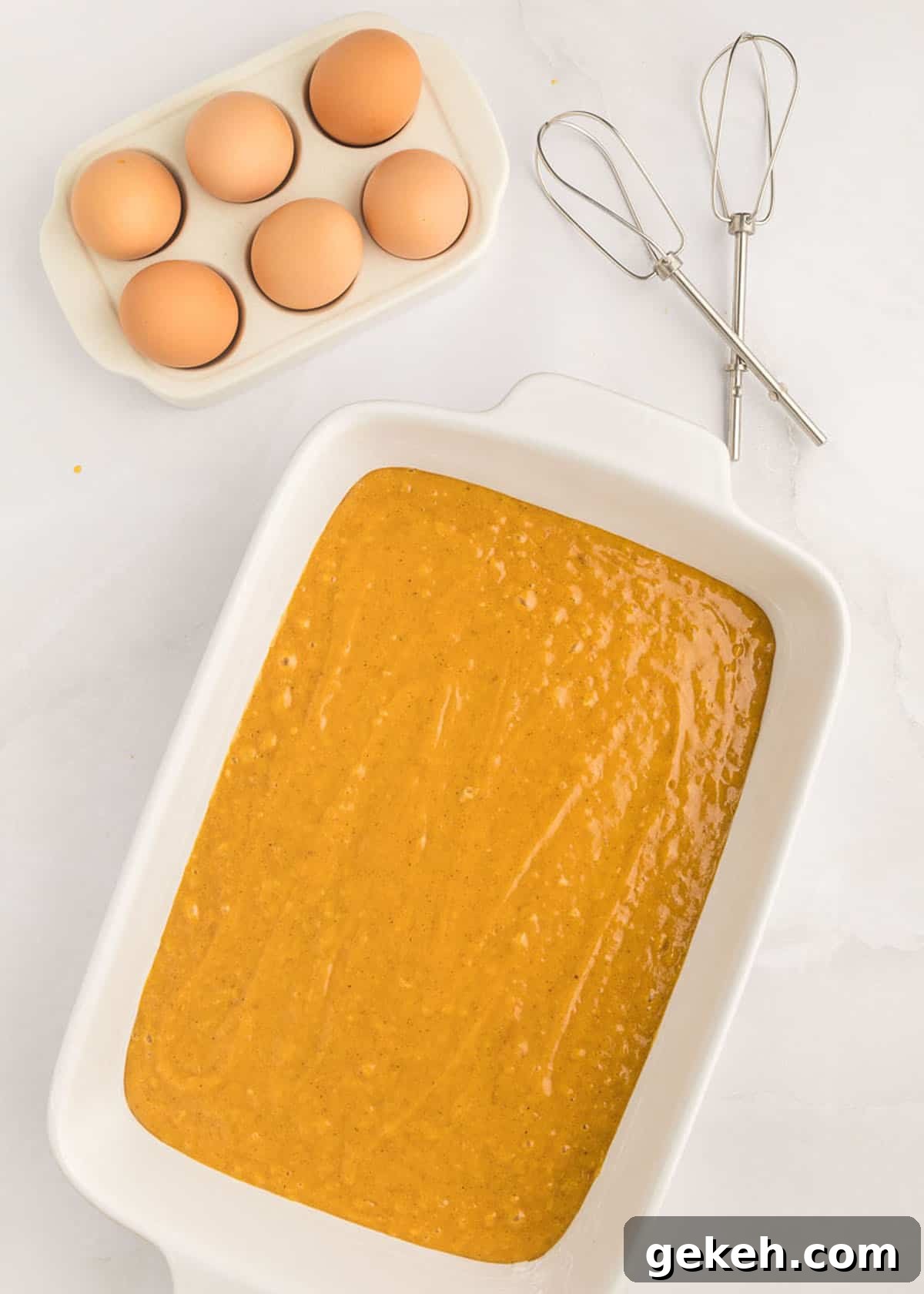 Moist Pumpkin Sheet Cake Recipe with Cream Cheese Frosting 14 A white baking dish filled with pumpkin cake batter.