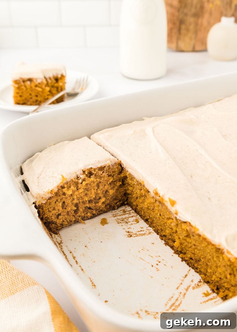 Moist Pumpkin Sheet Cake Recipe with Cream Cheese Frosting 21 Pumpkin cake in a white dish with a couple of slices missing.