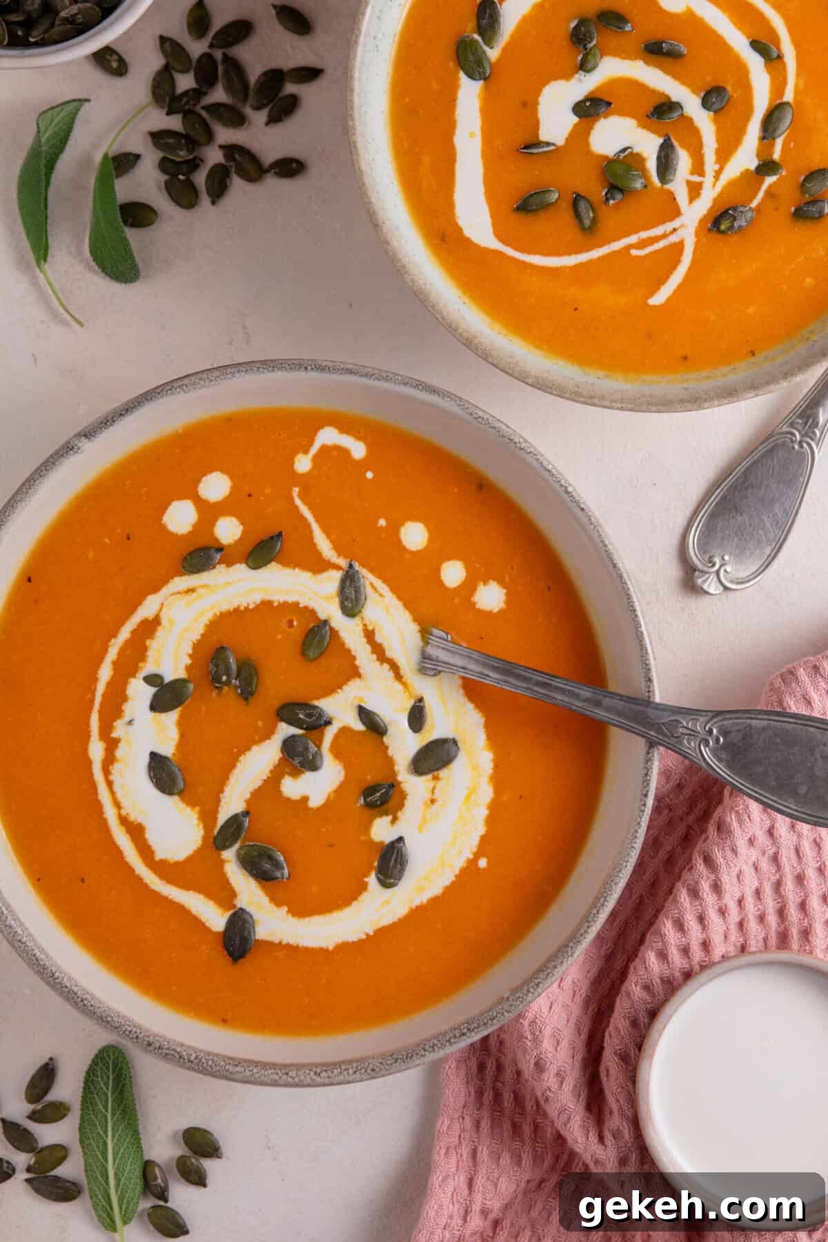Bowls of roasted pumpkin soup with swirls of cream and pumpkin seeds on top.