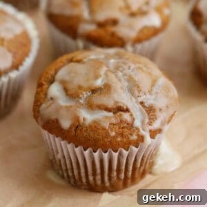 Gluten free pumpkin banana muffins with maple glaze on a sheet of parchment paper.