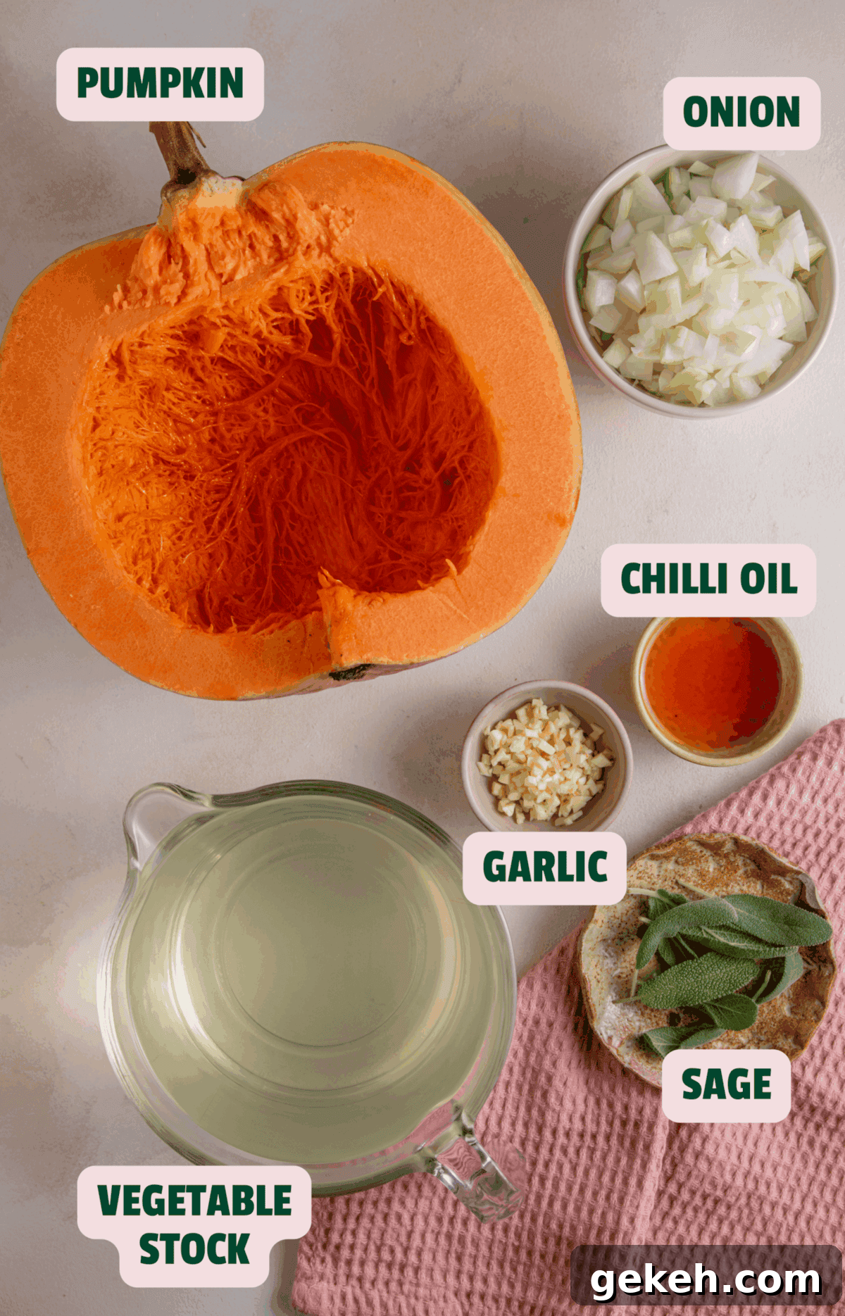 Ingredients for pumpkin soup including pumpkin, onions, stock, fresh herbs, garlic and oil.