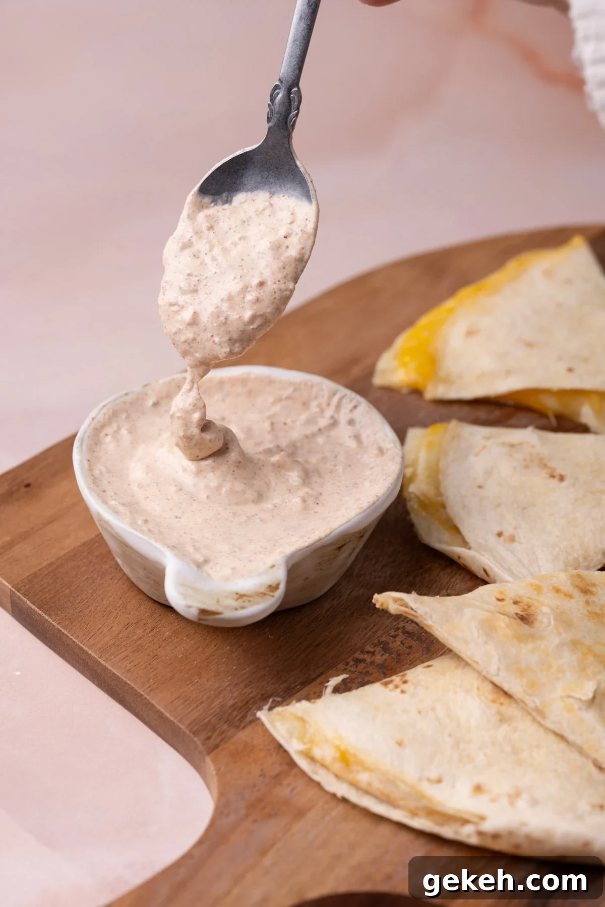 Creamy 3-Ingredient Quesadilla Sauce Recipe 2 Quesadilla sauce running off a spoon into a bowl of the sauce.