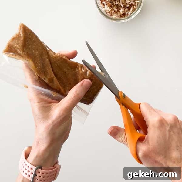 Clipping the corner off a snack bag filled with the caramel sauce with scissors.