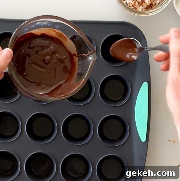 Spooning melted chocolate into mini muffin cups with a spoon.