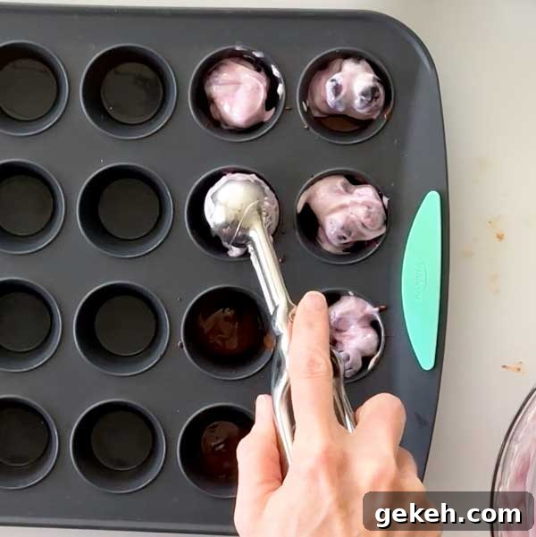 Scooping the blueberry yogurt mixture into the mini muffin cups.