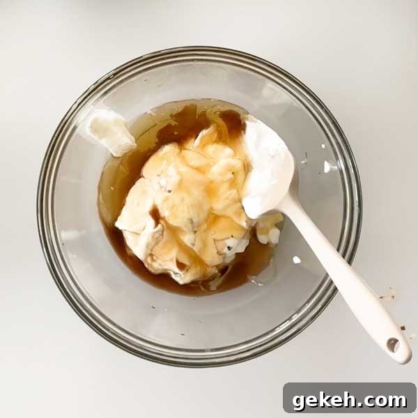 Adding yogurt ingredients to a glass mixing bowl.