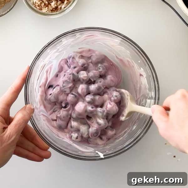 Mixing the blueberries in with the yogurt mixture with a spatula.