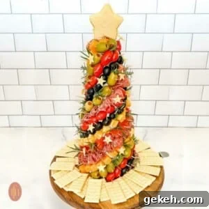 Festive Charcuterie Tree Guide: How to Build a Showstopping Holiday Platter 11 Decorated charcuterie tree standing vertically on a platter with a white background.