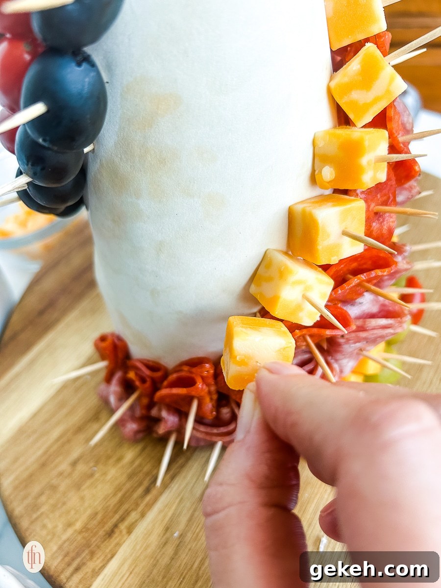 Festive Charcuterie Tree Guide: How to Build a Showstopping Holiday Platter 6 Placing a cube of cheese on a cone with a toothpick.