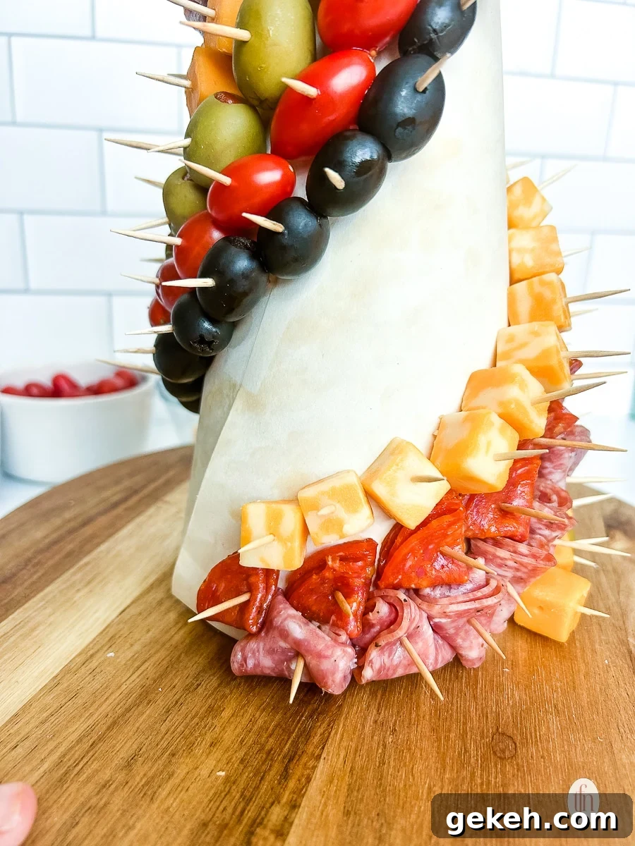Festive Charcuterie Tree Guide: How to Build a Showstopping Holiday Platter 7 Meats and cheeses pinned to a foam cone with toothpicks.