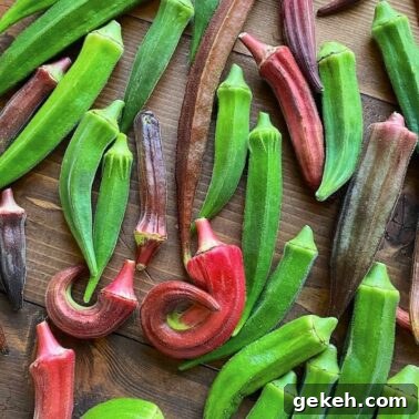 Perfectly Sautéed Summer Squash with Garlic and Herbs 9 A spread of fresh okra pods in varying shades of green and purple on a wooden surface.