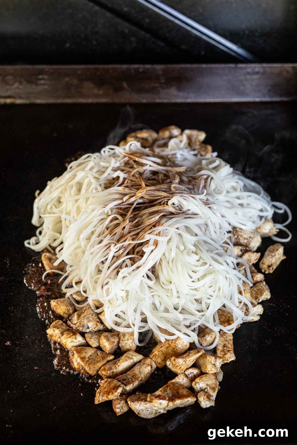 Authentic Pad Thai on a Blackstone Griddle: Simple Recipe 9 Cooking chicken on the griddle topped with cooked noodles