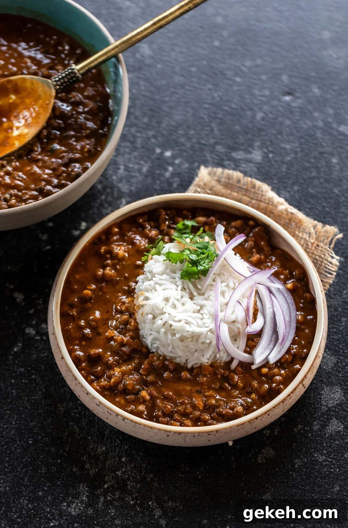 black lentils served with white rice in a bowl and topped with sliced onions and cilantro