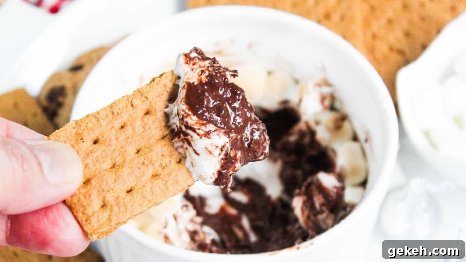 19 Desserts for Two to Share Straight from the Pan 5 A hand holding a graham cracker dipped in s'mores dip.