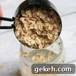 Creamy Peanut Butter Overnight Oats Recipe for Quick Breakfast 11 Rolled oats being added to the mason jar with the mixed liquid.